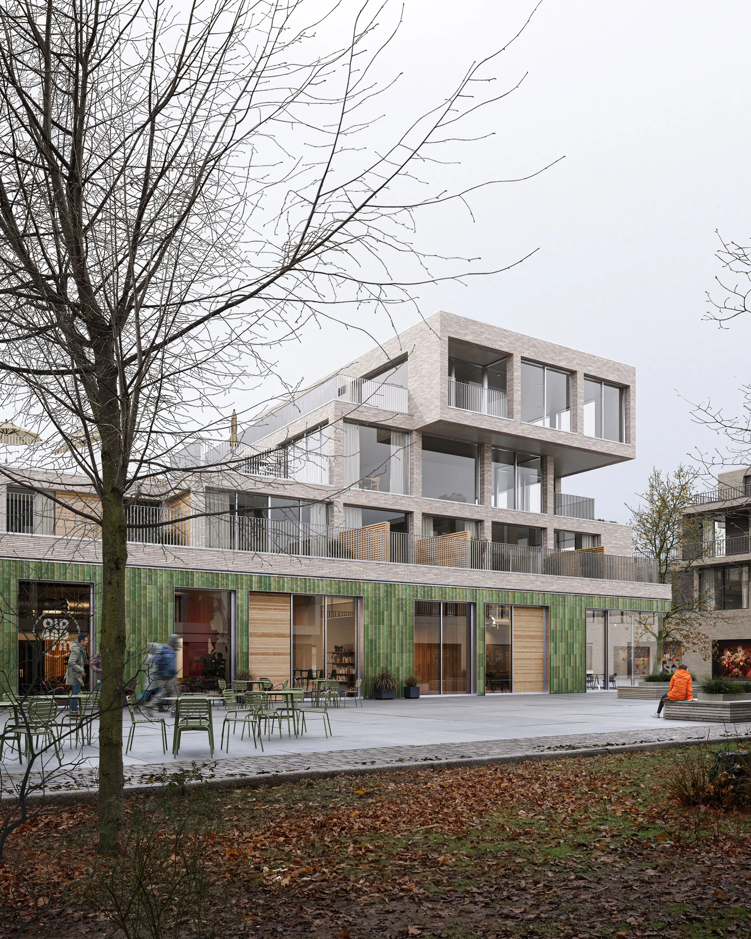 Mixed-use building with a green-tiled ground floor and brick upper storeys, with cafe seating on the square in autumn.