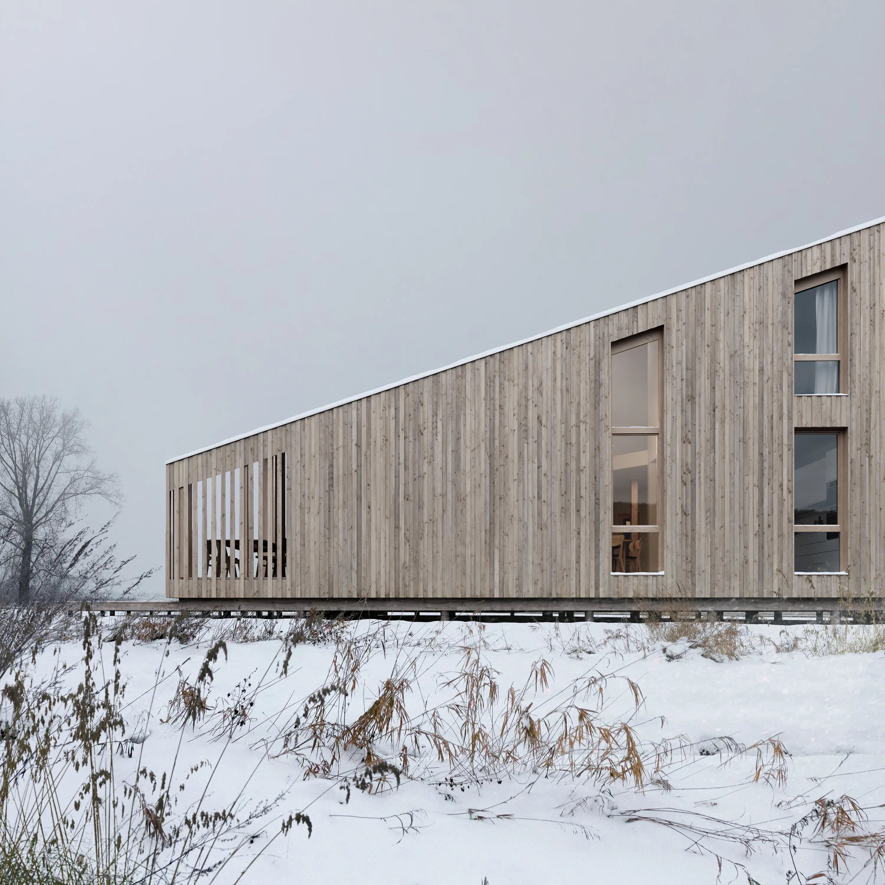 Long timber building in an open field covered with snow.